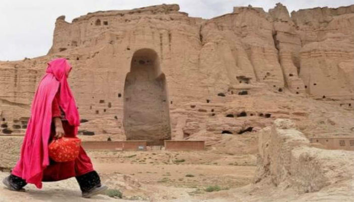 إحدى النساء تمر بالقرب من تمثال بوذا المدمر في أفغانستان