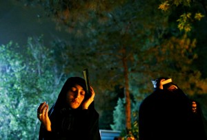 - سيدة شيعية تحمل القرآن بجانب رأسها أثناء الصلاة في إيران
