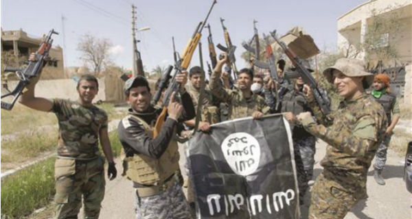 مقاتلون من القوات العراقية و«الحشد الشعبي» ينزلون راية لـ «داعش» في تكريت، أمس (رويترز)