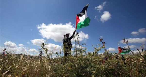فلسطيني يلوح بعلم بلاده خلال اشتباك مع قوات الاحتلال الاسرائيلي قرب رام الله امس (ا ف ب)