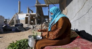 فلسطينية تحضر الطعام بجانب حطام منزلها، 22 يونيو 2015