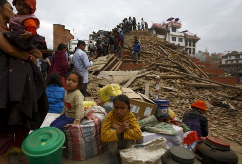 أشخاص يجلسون على جانب أمتعتهم في ساحة قرب معبد بعد زلزال مدمر في نيبال