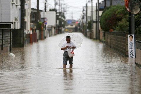 رجل يمشي في شارع مغمور بمياه نهر محلي في اليابان
