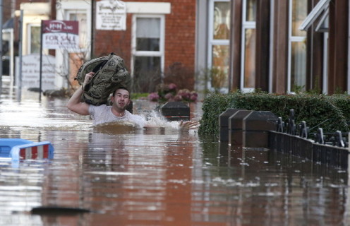 رجل من أهالي مدينة بريطانية يحمل حقيبته في شارع مغمور بالمياه
