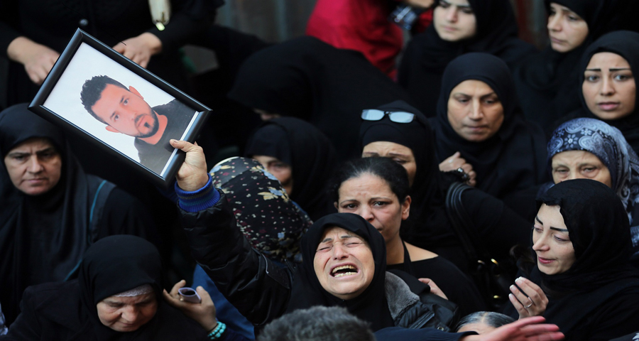 A relative of Samer Huhu, who was killed in a twin bombing attack that rocked a busy shopping street in the area of Burj al-Barajneh, waves his portrait as she mourns during his funeral in the southern suburb of the capital Beirut on November 13, 2015. Lebanon mourned 44 people killed in south Beirut in a twin bombing claimed by the Islamic State group, the bloodiest such attack in years, the Red Cross also said at least 239 people were also wounded, several in critical condition. AFP PHOTO/JOSEPH EID (Photo credit should read JOSEPH EID/AFP/Getty Images)