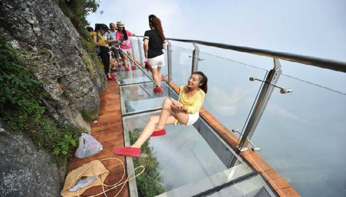 فتاة تلتقط الصور من على الجسر الزجاجي في جبل تيانمن في الصين