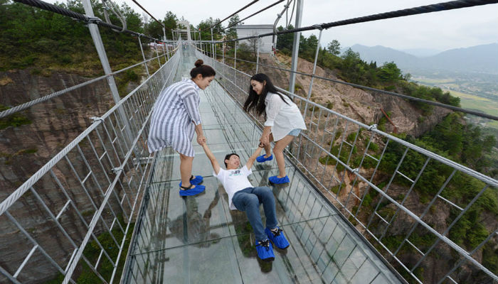 شاب لا يريد المشي على الجسر الزجاجي الخطير في الصين
