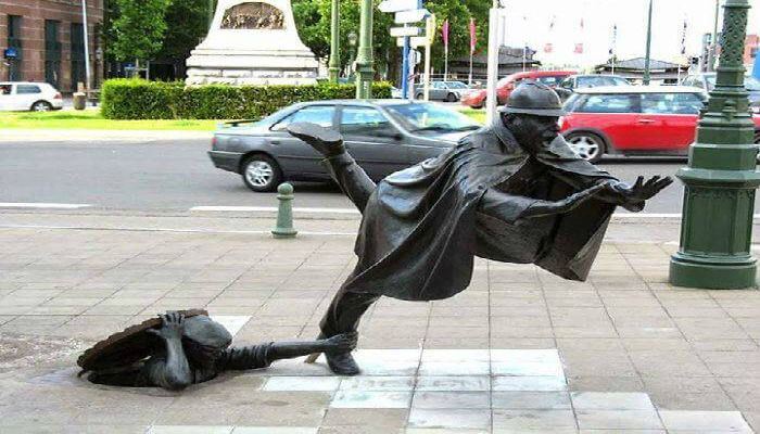 تمثال «دي فارتكابون» للفنان البلجيكي «توم فرانتزن» يتميز بروح الدعابة لرجل شرطي يجري فتعثر من قِبل رجل يختبئ في فتحة مياه الصرف الصحي، ويقع التمثال في سينت-جانس مولنبيك-بلجيكا.