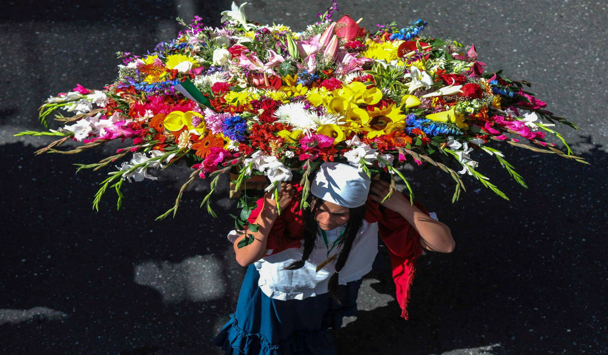 الفتاة تحمل الزهور المنسقة على ظهرها في مهرجان الزهور في كولومبيا