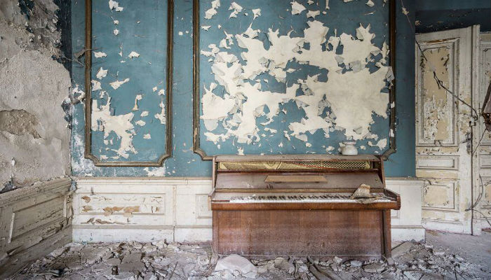 صورة لمكان مهجور من أوروبا يحتوي على الكثير من الخراب و بيانو منسي، بعدسة المصور «رومان ثيري»