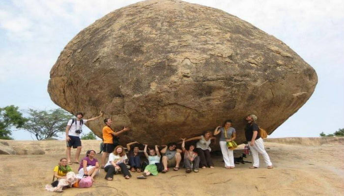 مجموعة من الناس تلتقط الصور بجانب صخرة كريشنا العملاقة في الهند