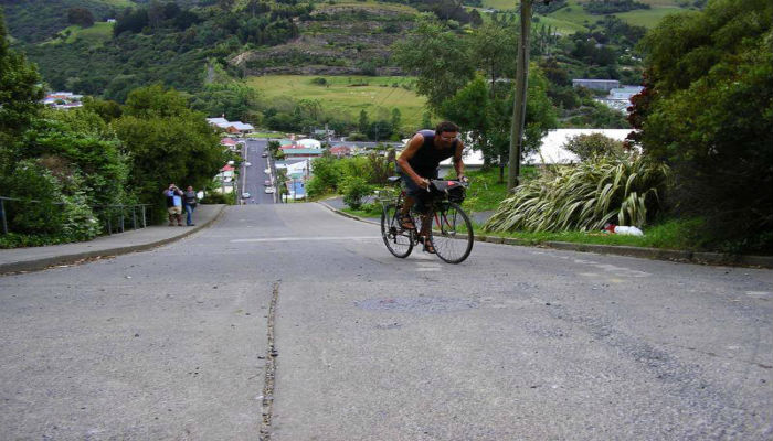 رجل يصعد بدراجاته الهوائية بصعوبة في شارع "بالدوين" في نيوزيلندا 