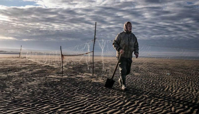 إمرأة تمشي في قرية "شوينا" الروسية على الرمال.