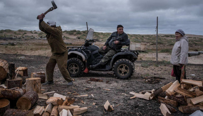 مجموعة رجال يعملون في تكسير الأخشاب في قرية "شوينا" الروسية.