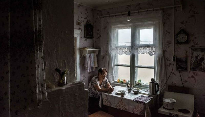 سيدة جالسة داخل منزلها الغارق بالرمال في قربة "شوينا" في روسيا.
