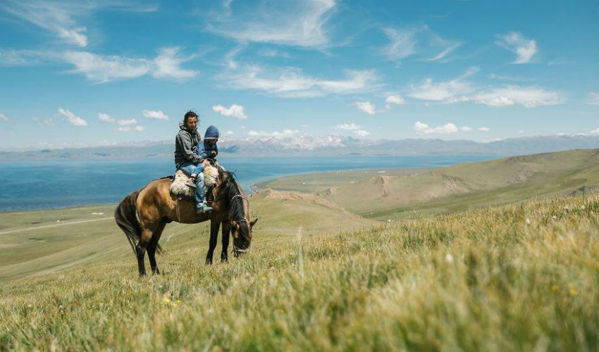 ركوب الأم والإبن النمساويان على الخيل في جبال قرغيزستان.