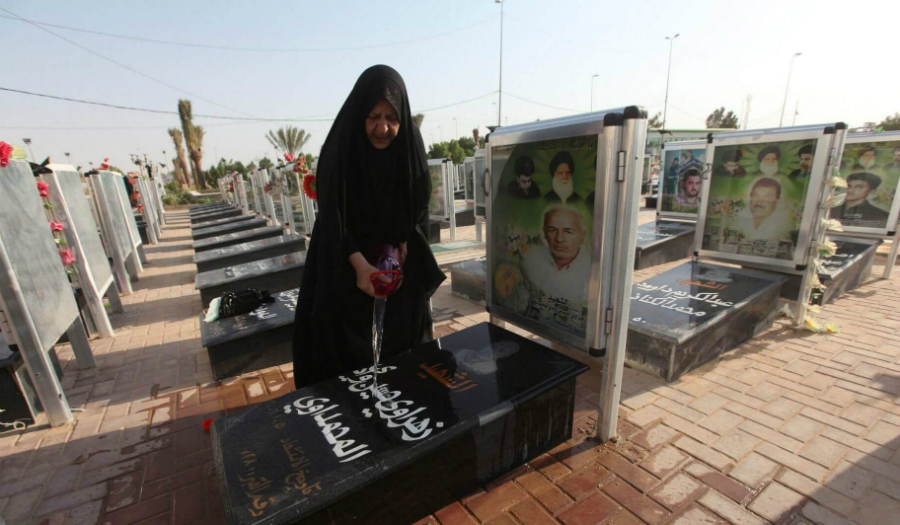 سيدة تنظف قبر زوجها الشهيد في مقبرة وادي السلام في العراق.