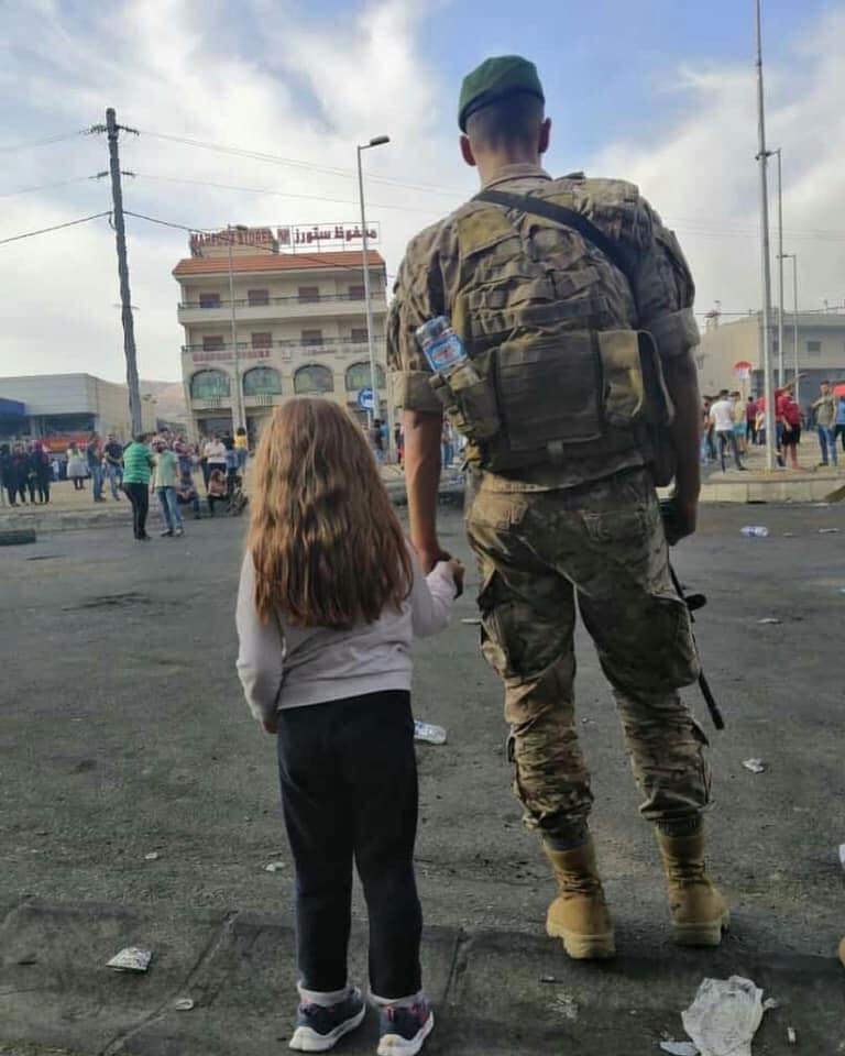 عسكري في الجيش اللبناني يمسك يد فتاة صغيرة
