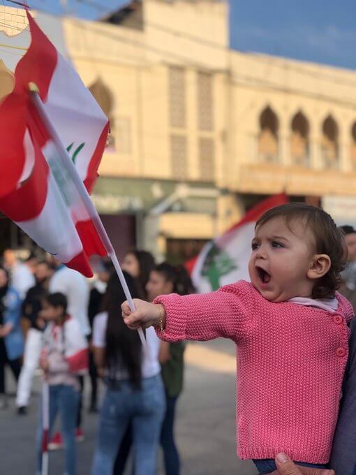 طفلة متظاهرة تحمل علم لبنان
