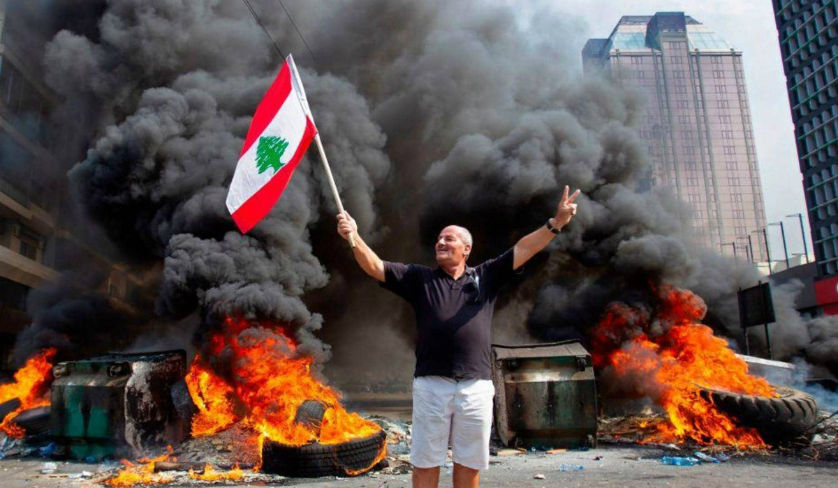 متظاهر يرفع علم لبنان