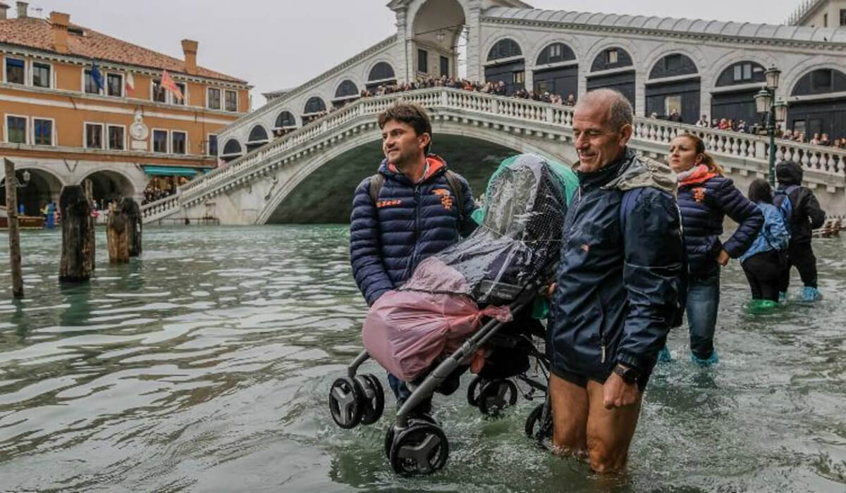 رجلان يتساعدان على حمل عربة وسط الفيضان العارم في مدينة البندقية "فينيسيا"