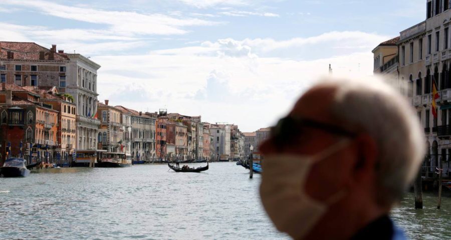 رجل يرتدي كمامة أمام القنال الكبير في البندقية ايطاليا وسط تفشي فيروس كورونا (رويترز)