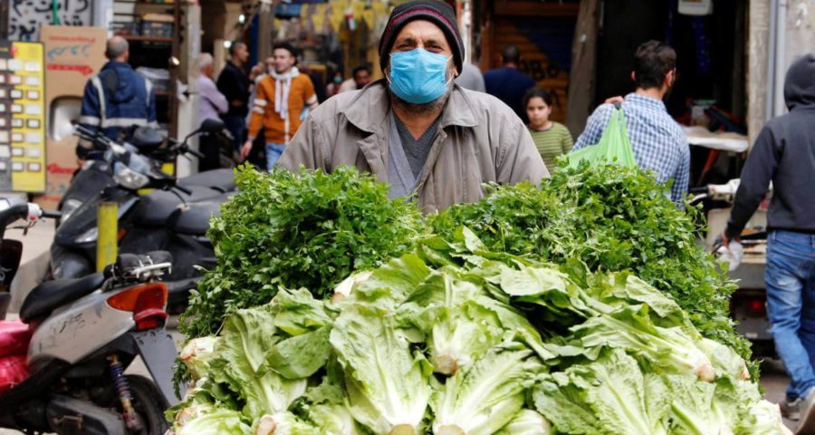 بائع خضار في مخيم شاتيلا في لبنان يرتدي كمامة للوقاية من فيروس كورونا (رويترز)