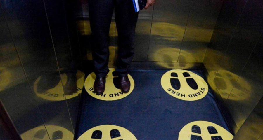 رجل في المصعد يلتزم باجراءات التباعد التي فرضها كورونا (AFP)