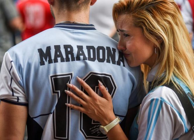 فتاة تبكي إلى جانب شاب يرتدي قميص مارادونا