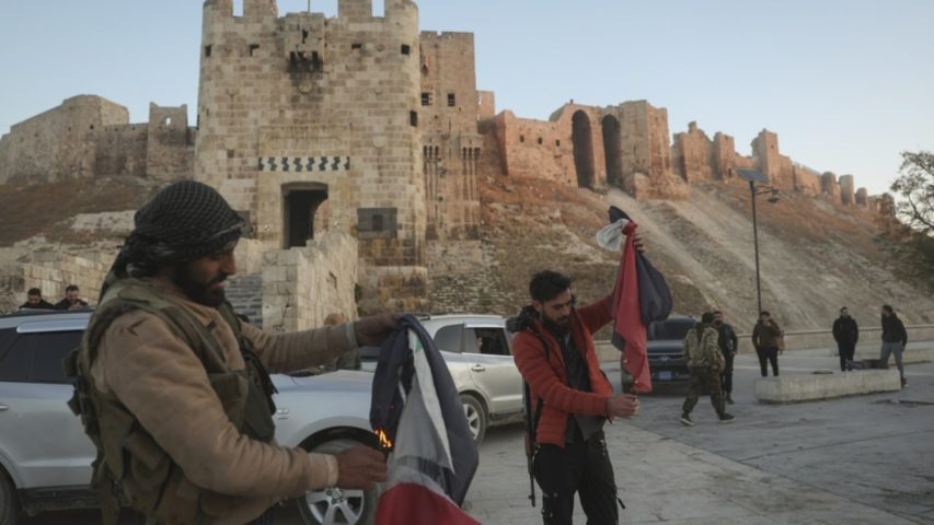 Syrian opposition fighters burn government Syrian flags for the cameras next to Aleppo's old city (AP)