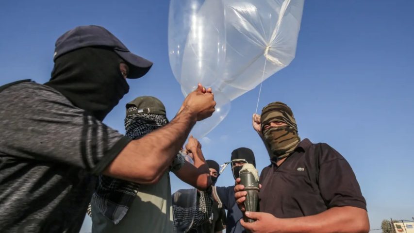 Palestinians attaching an incendiary device to inflated condoms to be flown toward Israel on Aug 21, 2020 (Getty)