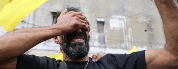 A man reacts while holding a Hezbollah flag (AFP)