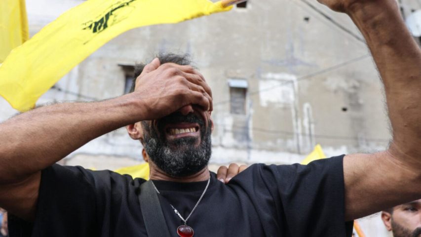 A man reacts while holding a Hezbollah flag (AFP)