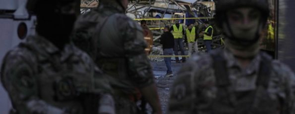 Civil defence workers and Lebanese soldiers gather at the site of an Israeli airstrike in Dahiyeh today (AP)