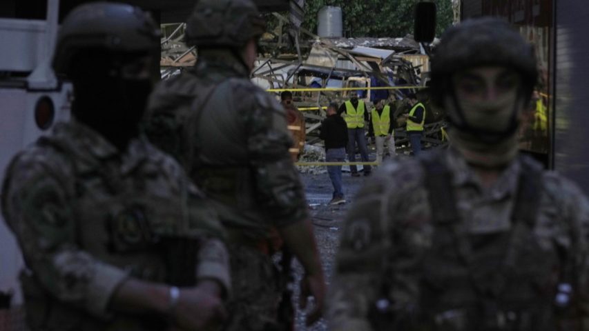 Civil defence workers and Lebanese soldiers gather at the site of an Israeli airstrike in Dahiyeh today (AP)