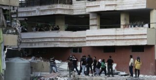 Residents inspect the area following an Israeli airstrike on Dahiyeh (AP)